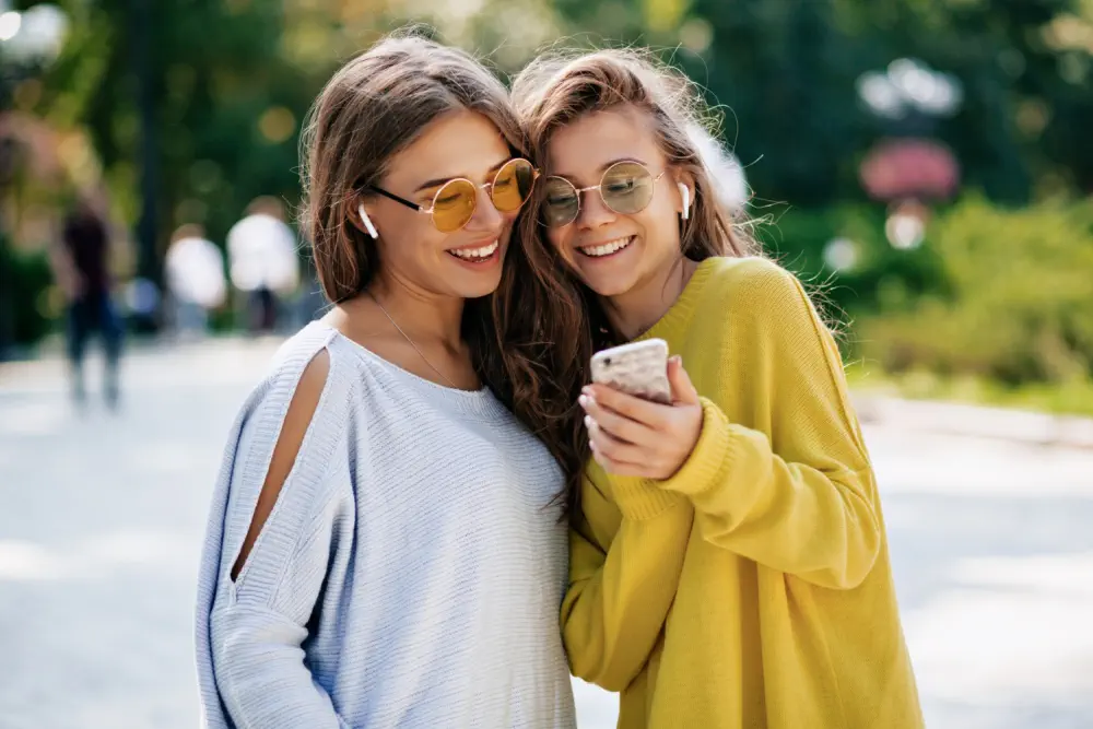 Two young women smiling and looking at a smartphone