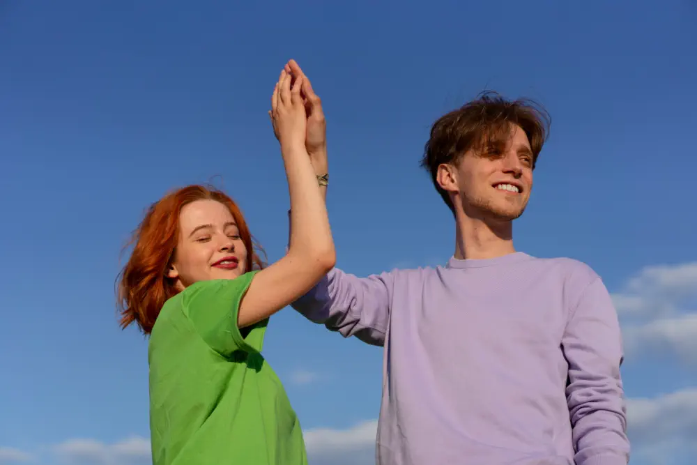 Couple holding hands up against a blue sky