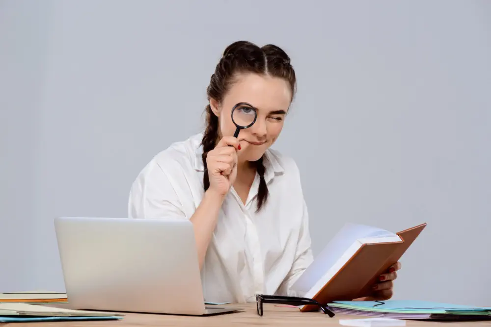 Woman using a magnifying glass to read book.