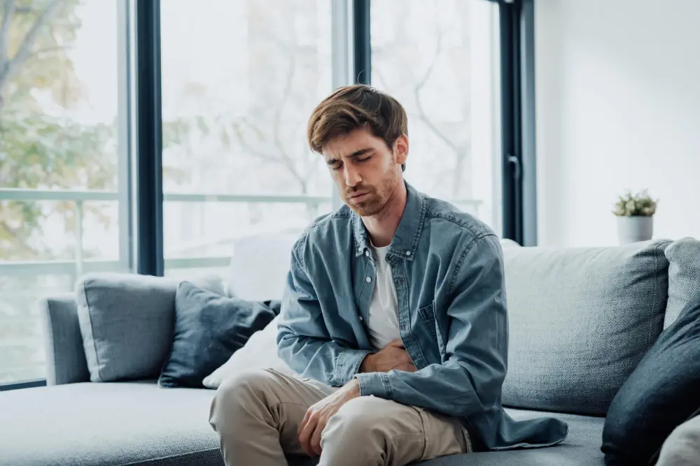 Man holding his midsection in distress, representing kidney or liver damage.